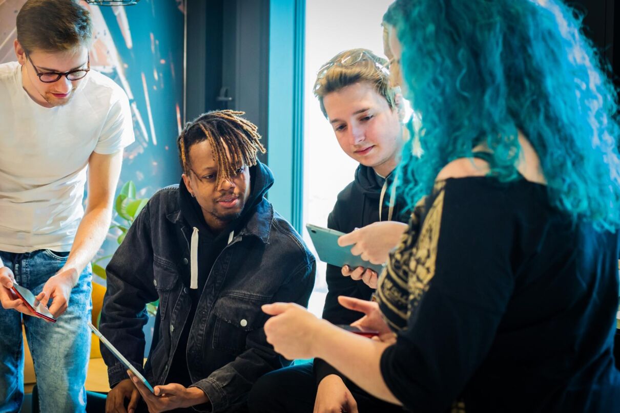A group of employees standing around in the office while holding tablets.